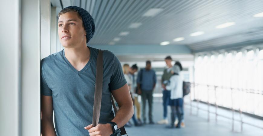 Étudiant appuyé contre une fenêtre dans un couloir