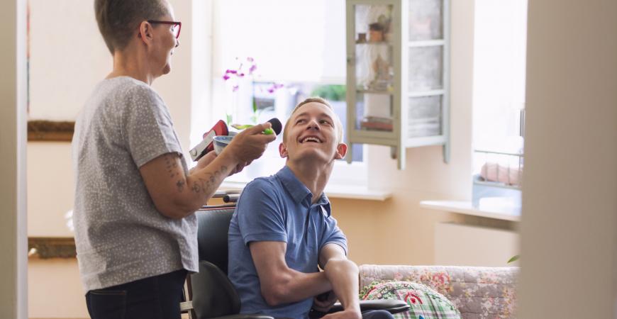 Individual in a wheelchair talking to someone standing beside them